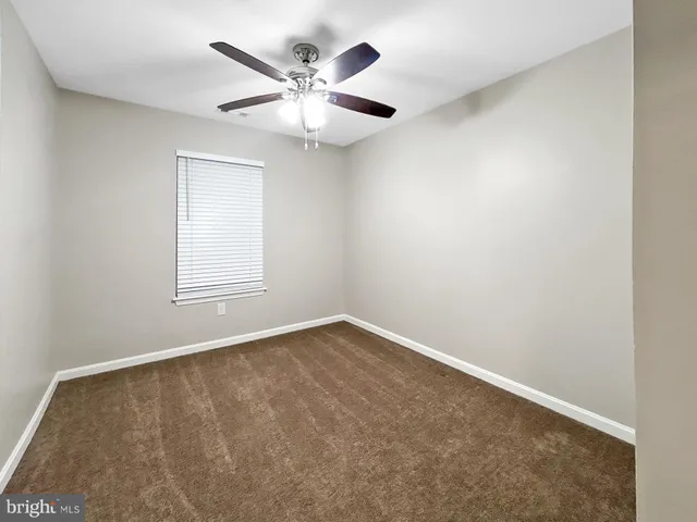 an empty room with a chandelier fan and windows