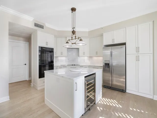 a kitchen with kitchen island a stove a refrigerator and a chandelier
