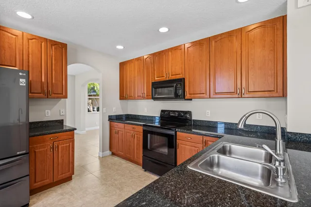 a kitchen with granite countertop a sink stove and cabinets