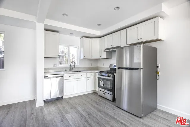 a kitchen with granite countertop white cabinets and stainless steel appliances