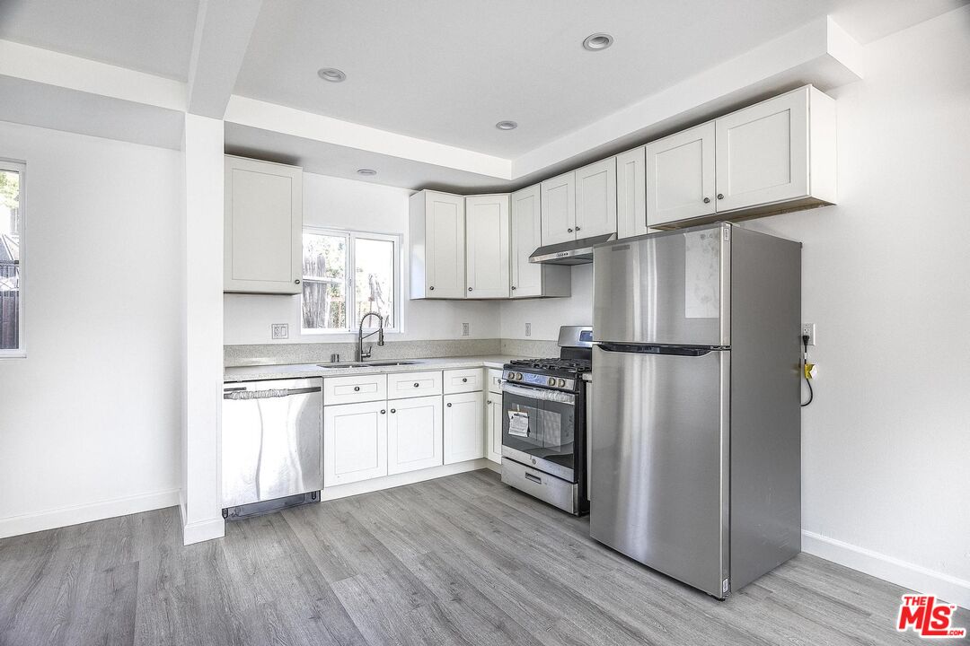 1324 Toberman Street, Unit 1/4 Los Angeles, CA 90015 - Photo 1 of 12 a kitchen with granite countertop white cabinets and stainless steel appliances