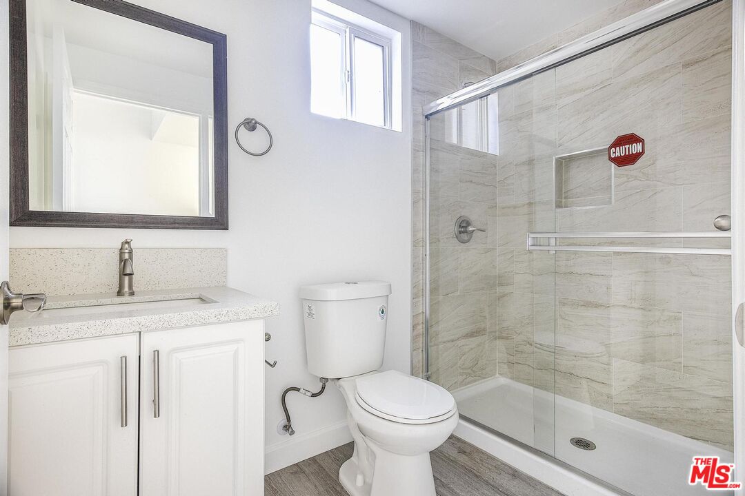 1324 Toberman Street, Unit 1/4 Los Angeles, CA 90015 - Photo 7 of 12 a bathroom with a granite countertop sink toilet a shower and a mirror