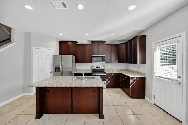 a kitchen with kitchen island granite countertop a stove sink and cabinets