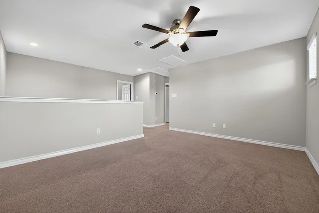 an empty room with ceiling fan and window
