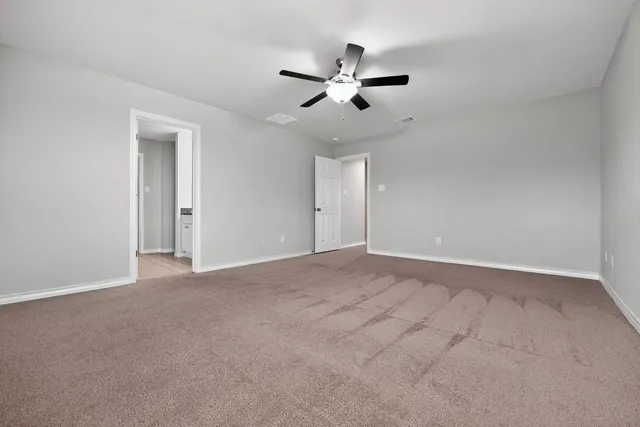 a view of an empty room with chandelier fan