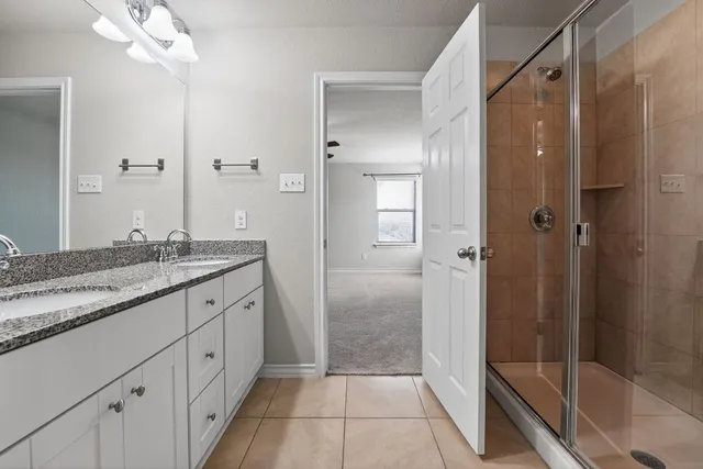 a bathroom with a granite countertop sink a mirror and a shower