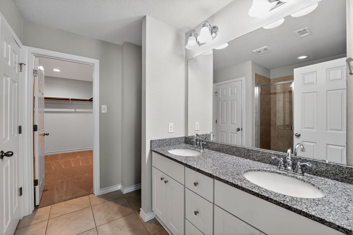 548 Appalachian Trail Leander, TX 78641 - Photo 26 of 38 a bathroom with a granite countertop double vanity sink a mirror and a shower