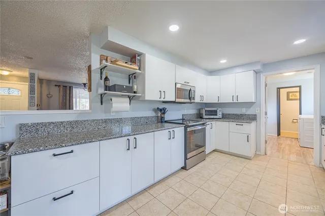 a kitchen with granite countertop white cabinets white stainless steel appliances with a sink and dishwasher