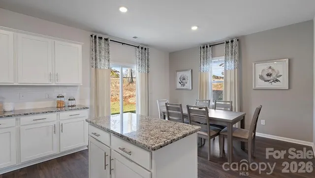 a kitchen with granite countertop white cabinets and chairs
