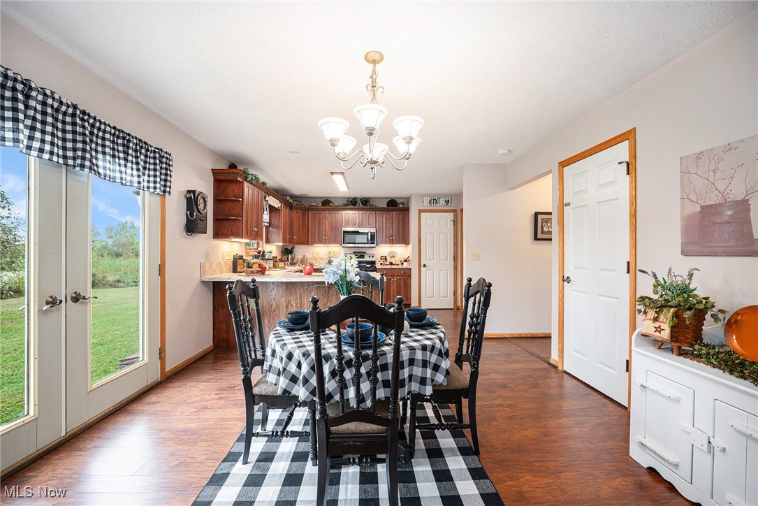 2073 Sexton Road Austinburg, OH 44010 - Photo 10 of 32 Dining space with dark wood-style flooring, french doors, and a chandelier