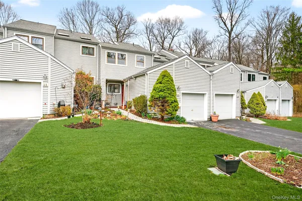 a view of a white house next to a yard with big trees