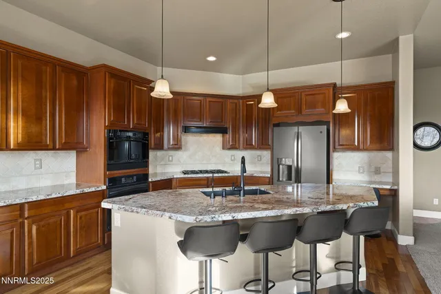 a kitchen with kitchen island granite countertop a stove a sink island and a refrigerator