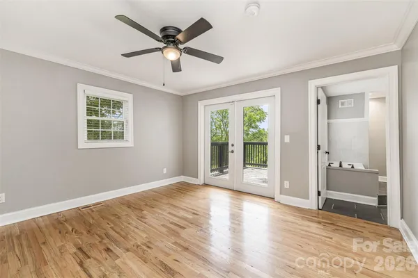 a view of an empty room with a window and wooden floor