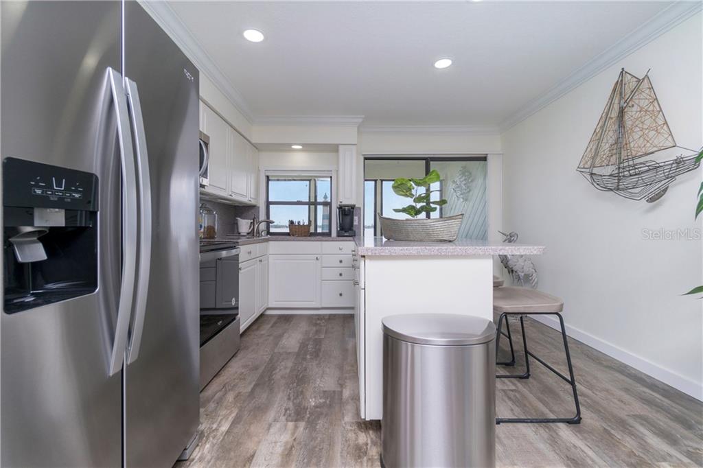 5041 North Beach Road, Unit 3A Englewood, FL 34223 - Photo 14 of 52 a kitchen with stainless steel appliances a refrigerator sink and wooden floor