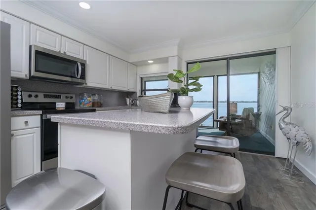 a kitchen with stainless steel appliances granite countertop a sink dishwasher stove top oven a dining table and chairs with wooden floor