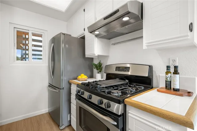 a kitchen with stainless steel appliances granite countertop a stove and a refrigerator with wooden floor