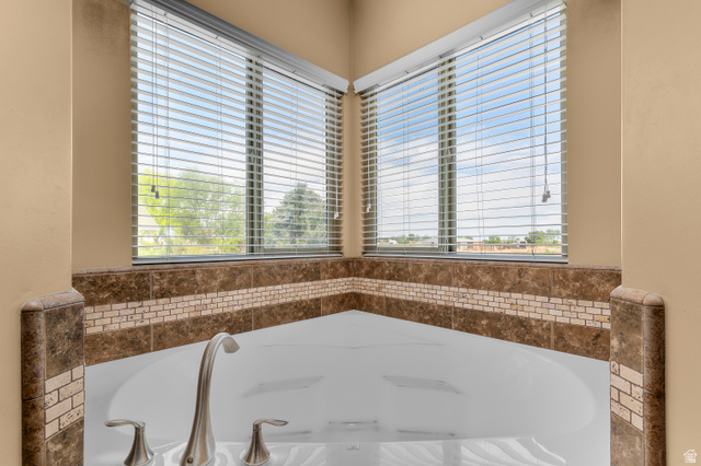 5702 950 North Ogden, UT 84404 - Photo 27 of 36 Corner soaking tub featuring brushed nickel fixtures, a tiled surround with a mosaic accent band, and two large windows with blinds