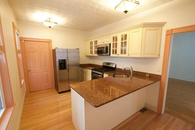 a kitchen with stainless steel appliances granite countertop a sink a refrigerator and wooden floor