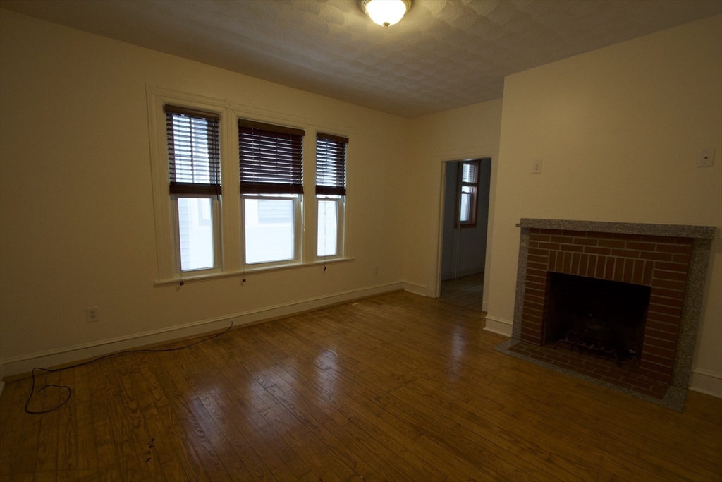 31 Dunreath Street, Unit 1 Boston, MA 02119 - Photo 3 of 11 a view of an empty room with wooden floor fireplace and a window
