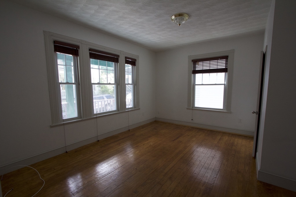 31 Dunreath Street, Unit 1 Boston, MA 02119 - Photo 4 of 11 a view of an empty room with wooden floor and a window