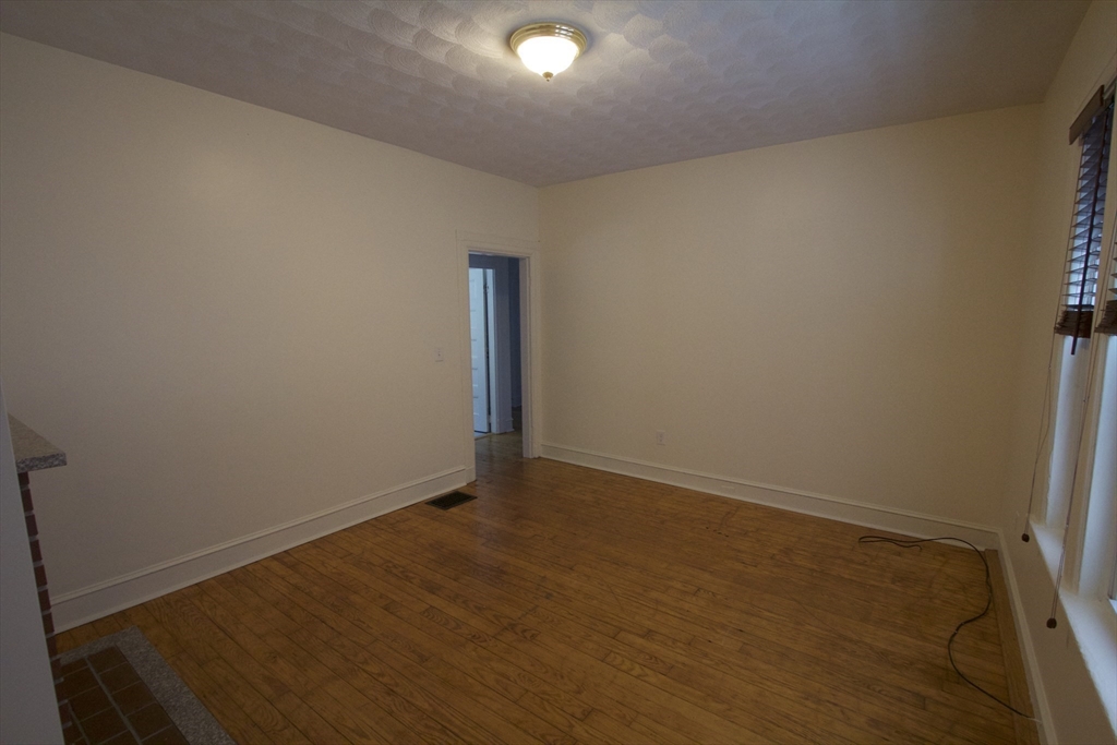 31 Dunreath Street, Unit 1 Boston, MA 02119 - Photo 6 of 11 an empty room with wooden floor and windows