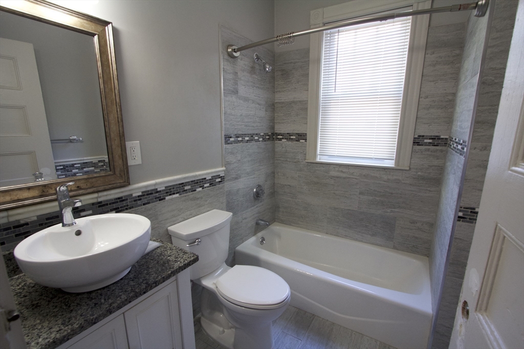 31 Dunreath Street, Unit 1 Boston, MA 02119 - Photo 9 of 11 a bathroom with a granite countertop sink toilet and shower