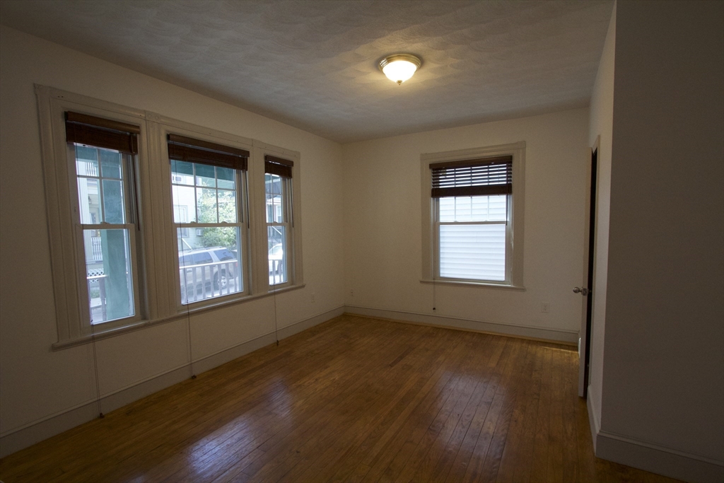 31 Dunreath Street, Unit 1 Boston, MA 02119 - Photo 10 of 11 an empty room with wooden floor and windows