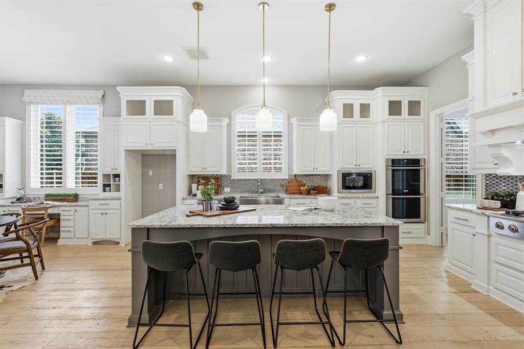 1933 Snapdragon Road Frisco, TX 75033 - Photo 11 of 40 Expansive kitchen featuring a large island with seating, pendant lighting, white cabinetry, integrated double ovens, and wood-finish flooring