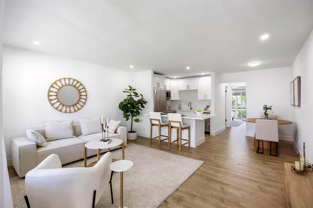 a living room with furniture kitchen view and a large window