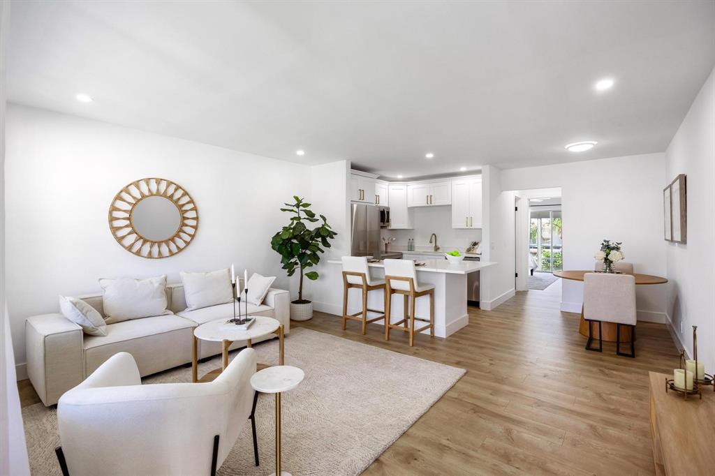 a living room with furniture kitchen view and a large window