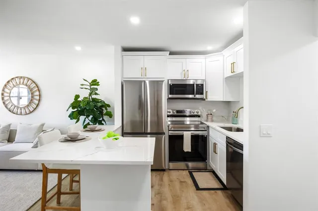 a kitchen with stainless steel appliances a sink a stove a refrigerator cabinets and a dining table