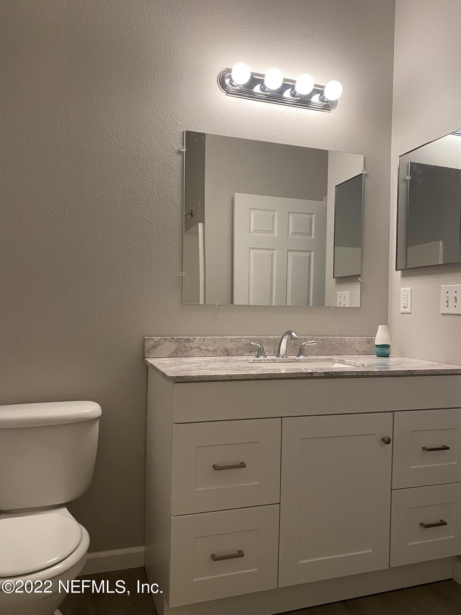 7920 Merrill Road, Unit 101 Jacksonville, FL 32277 - Photo 11 of 14 a bathroom with a granite countertop toilet sink and mirror