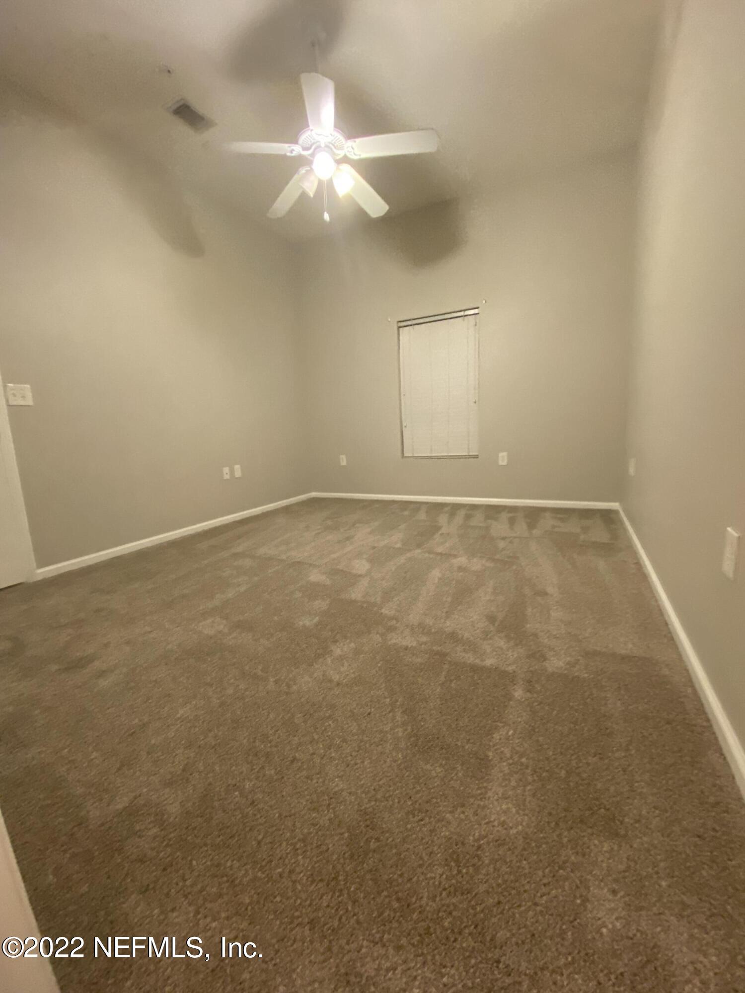 7920 Merrill Road, Unit 101 Jacksonville, FL 32277 - Photo 8 of 14 an empty room with a chandelier fan and windows