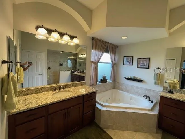 a bathroom with a granite countertop tub sink and mirror