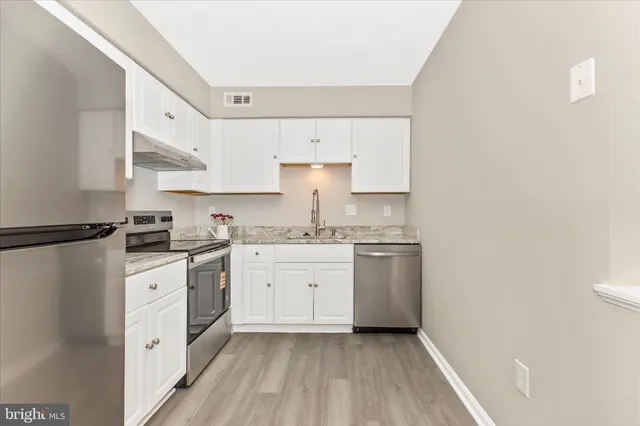 a kitchen with granite countertop white cabinets and white appliances