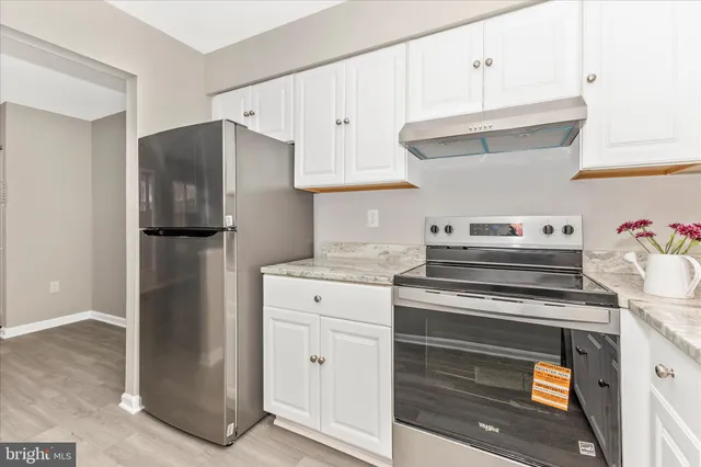 a kitchen with stainless steel appliances white cabinets and a refrigerator