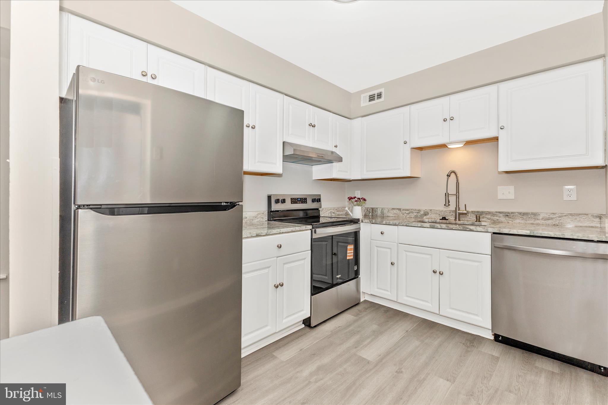 2861 Shepperton Terrace Silver Spring, MD 20904 - Photo 18 of 44 a kitchen with granite countertop a refrigerator a sink and white cabinets