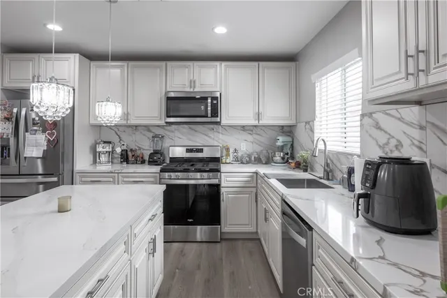 a kitchen with stainless steel appliances a sink dishwasher a stove top oven a refrigerator with island and cabinets