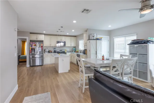 a kitchen with stainless steel appliances granite countertop a refrigerator a stove top oven a sink dishwasher and white cabinets with wooden floor