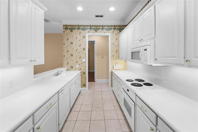 a large white kitchen with granite countertop a sink a stove refrigerator and cabinets
