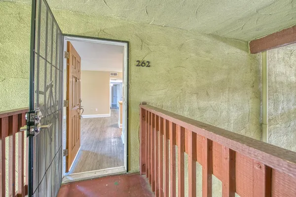 a view of an empty room with a window and wooden floor