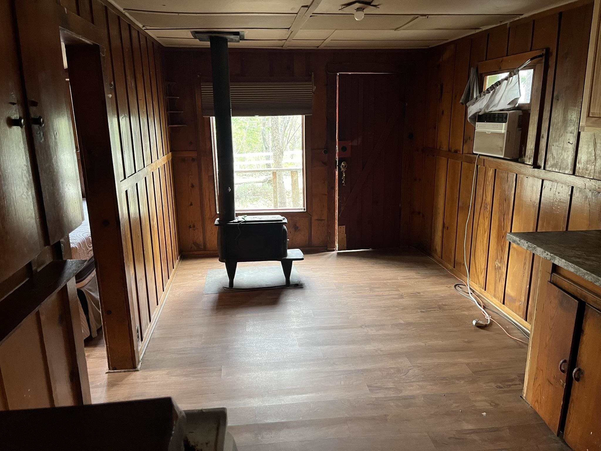 23090 North Bald Mountain Road Sonora, CA 95370 - Photo 28 of 59 Miscellaneous room with a wood stove, wood walls, and light wood-style floors
