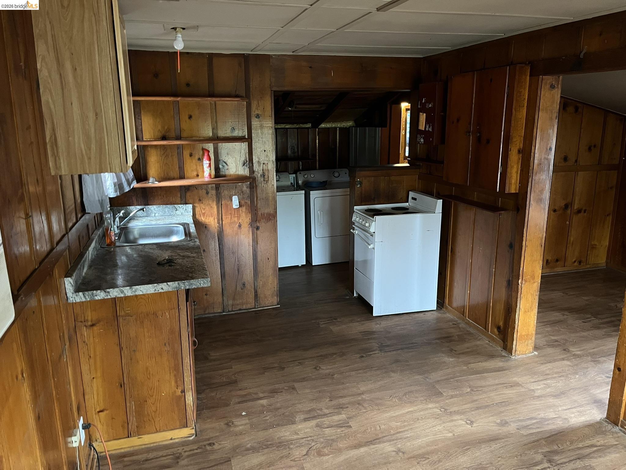 23090 North Bald Mountain Road Sonora, CA 95370 - Photo 29 of 59 Kitchen featuring wooden walls, white electric range, open shelves, dark wood-type flooring, and independent washer and dryer