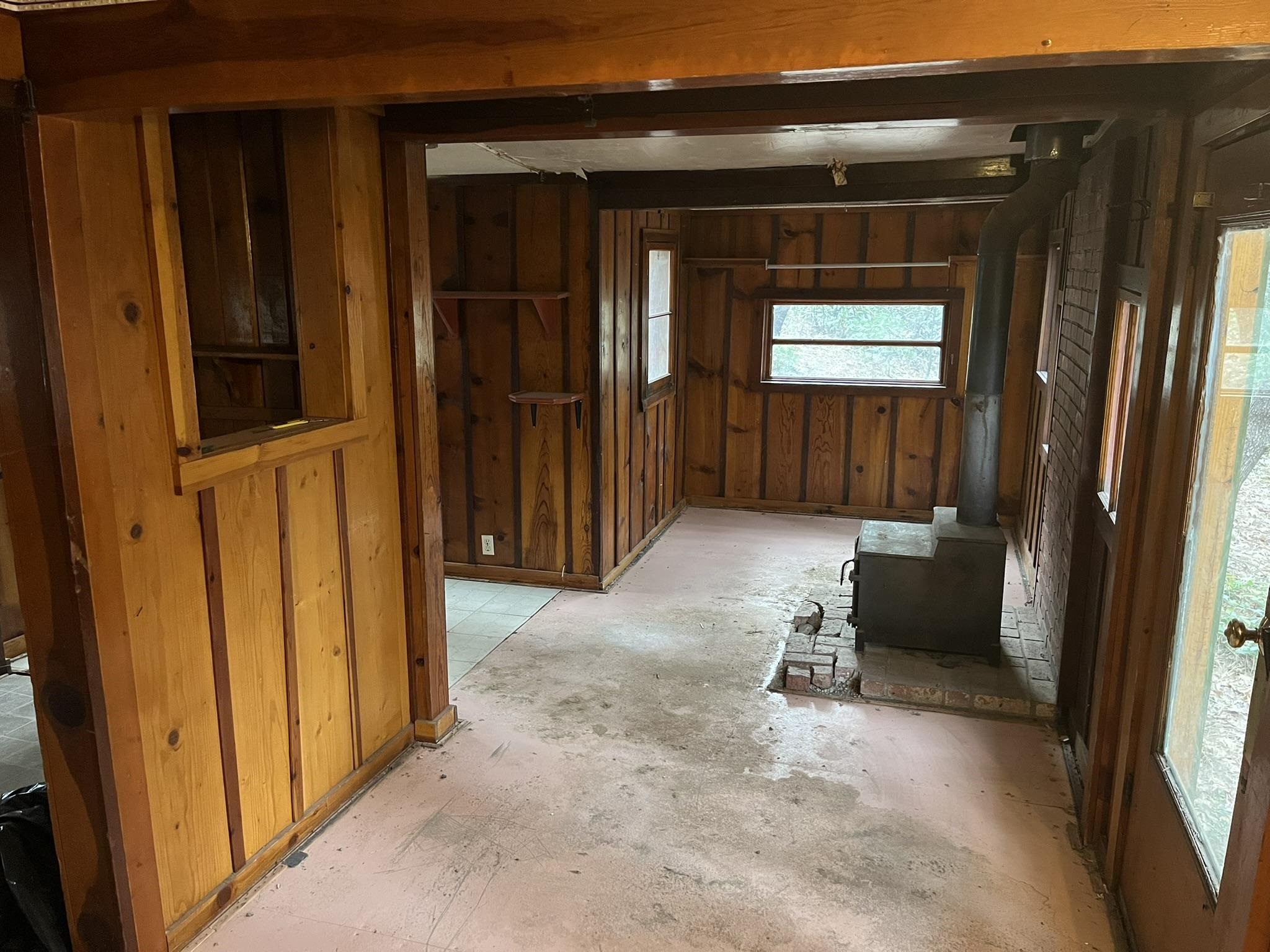 23090 North Bald Mountain Road Sonora, CA 95370 - Photo 35 of 59 Misc room with a wood stove, wood walls, and unfinished concrete flooring