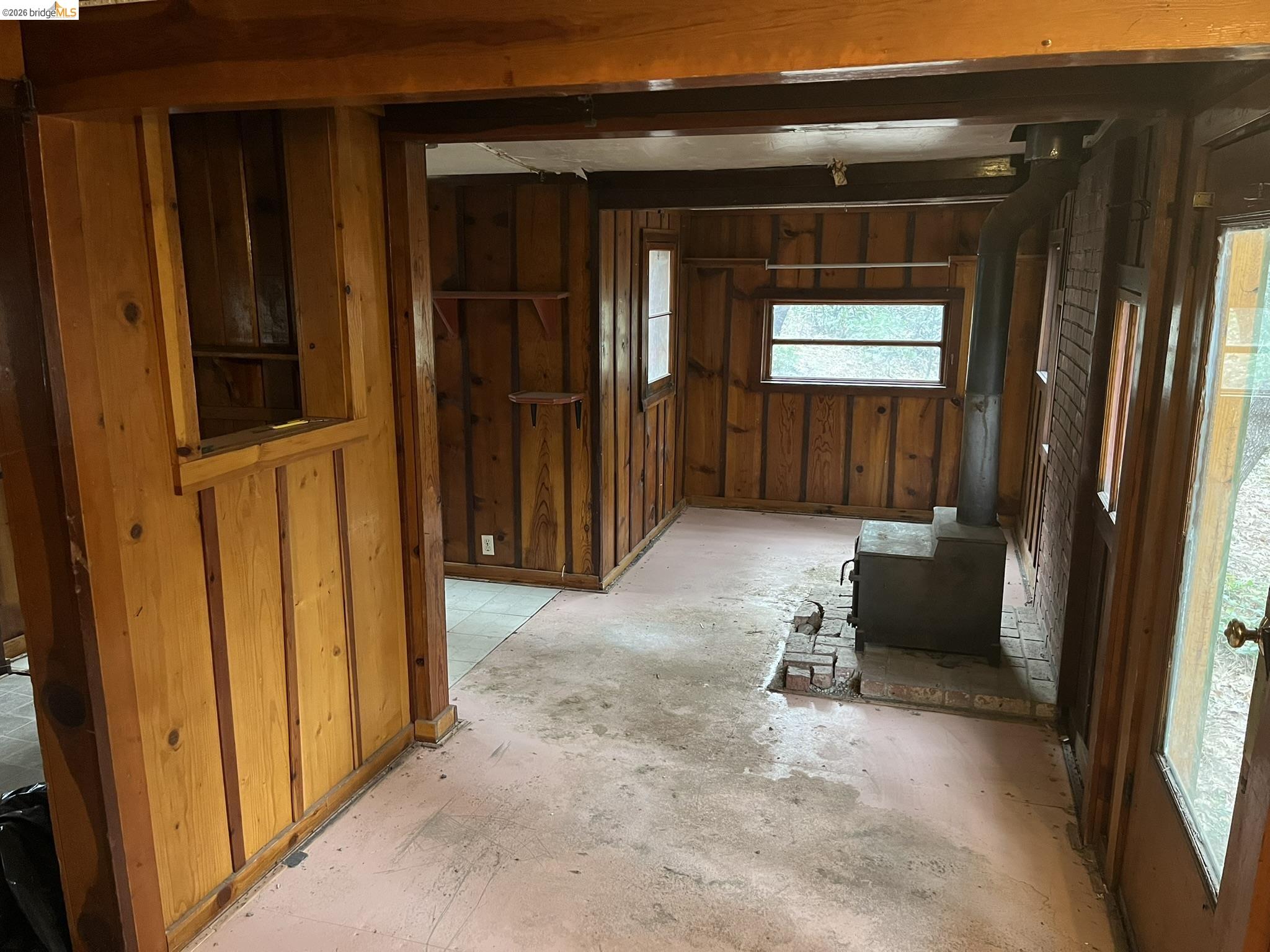 23090 North Bald Mountain Road Sonora, CA 95370 - Photo 37 of 59 Misc room with a wood stove, wood walls, and unfinished concrete flooring
