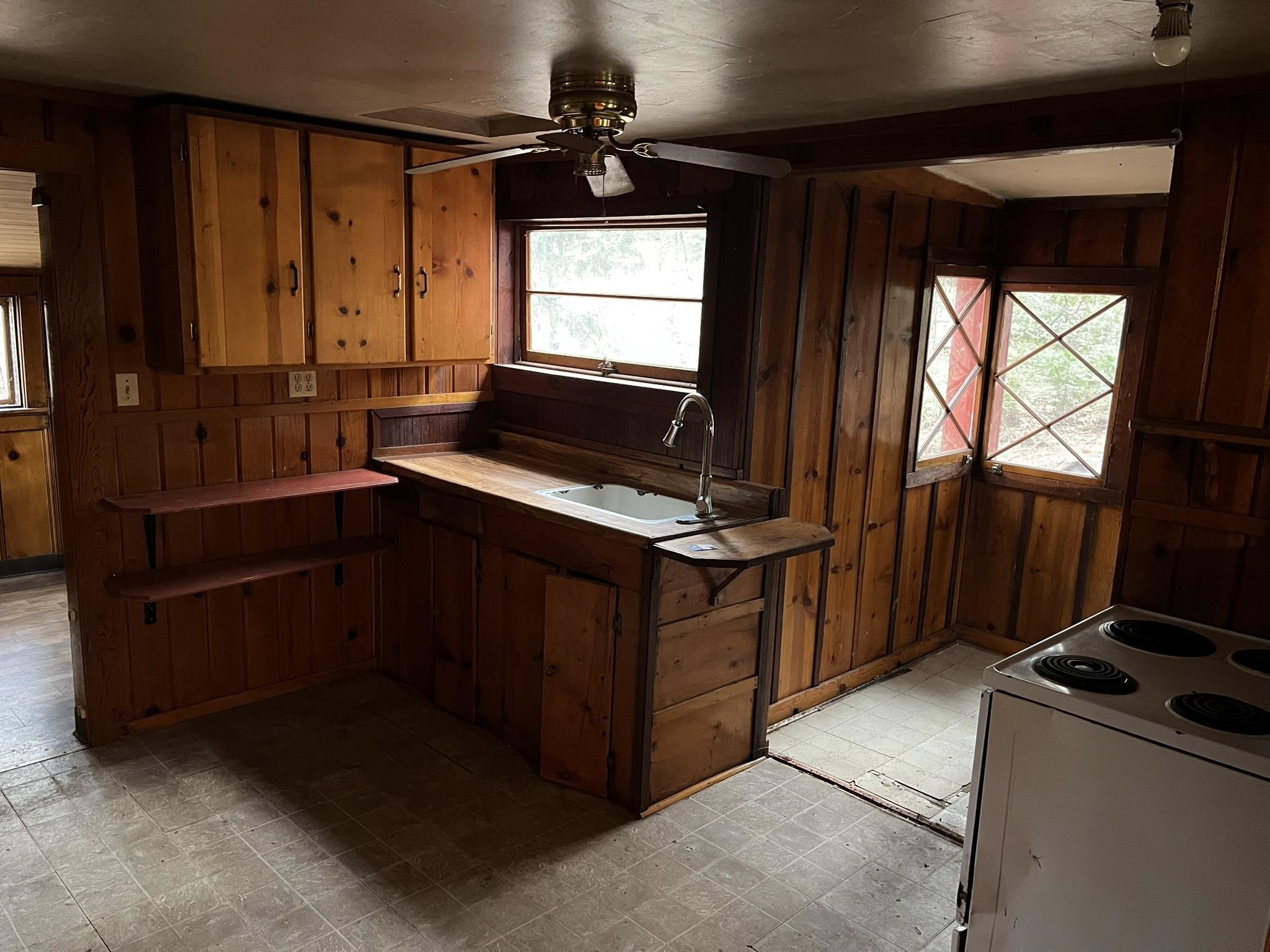 23090 North Bald Mountain Road Sonora, CA 95370 - Photo 39 of 59 Kitchen featuring wood walls, white electric range, light floors, and a ceiling fan