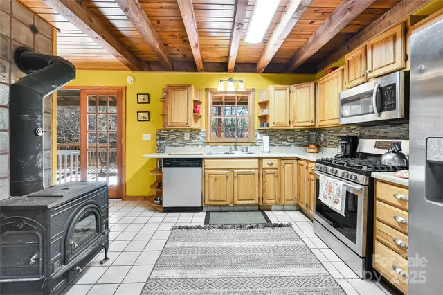 a kitchen with stainless steel appliances granite countertop a stove a sink dishwasher and white cabinets with wooden floor