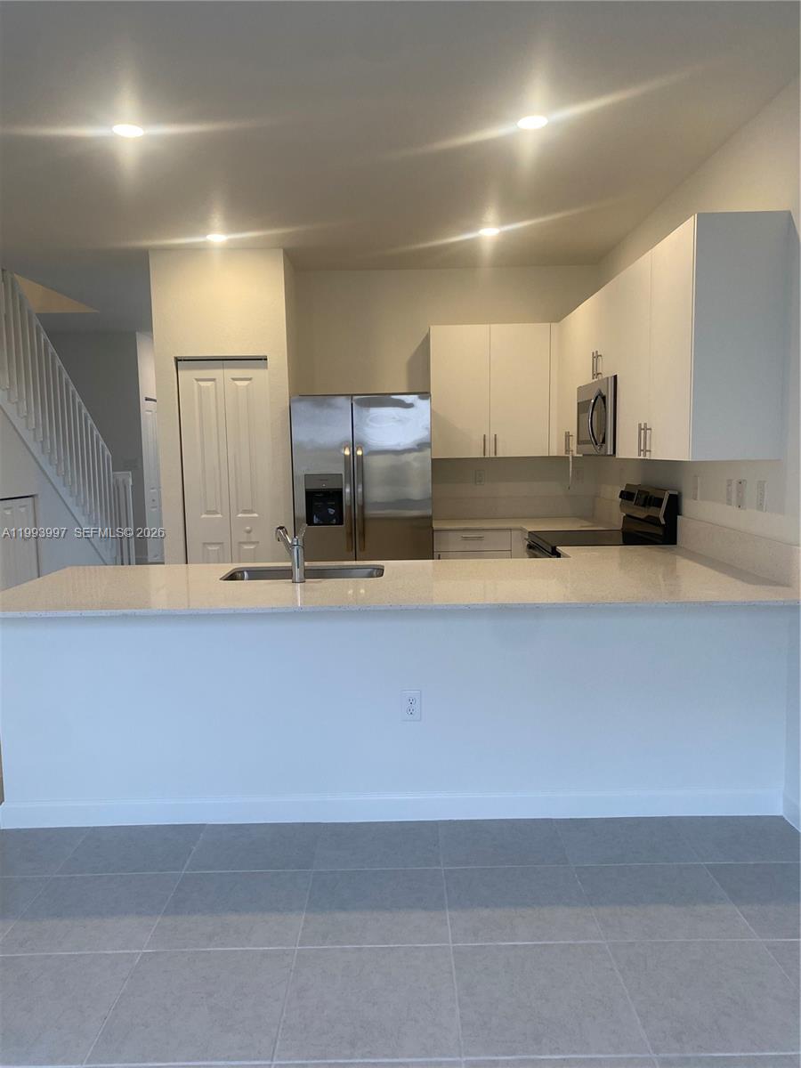 12773 Southwest 234th Terrace Homestead, FL 33032 - Photo 8 of 11 a kitchen with kitchen island white cabinets and stainless steel appliances