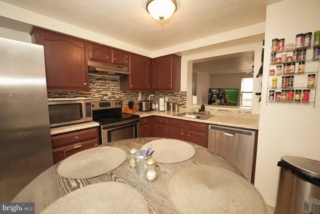 a kitchen with stainless steel appliances a dining table and chairs