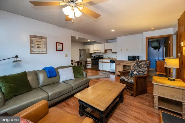 a living room with furniture kitchen view and a wooden floor